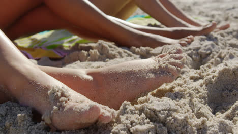 Young-female-friends-sitting-together-in-sand-4k