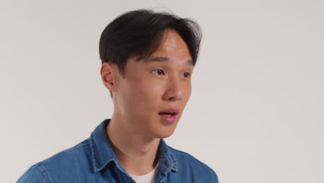 색 스튜디오 배경 앞의 남자가 사진 부스 스타일의 초상화를 위해 포즈를 취하고 있습니다.