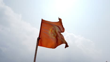 Eine-Safranfarbene-Hinduistische-Flagge,-Die-Tagsüber-Weht,-Mit-Dem-Himmel-Und-Wolken-Im-Hintergrund