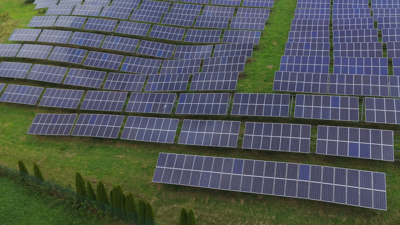 Aerial drone view of a solar farm in Roana, Italy. Rows of photovoltaic panels over green fields generate renewable energy