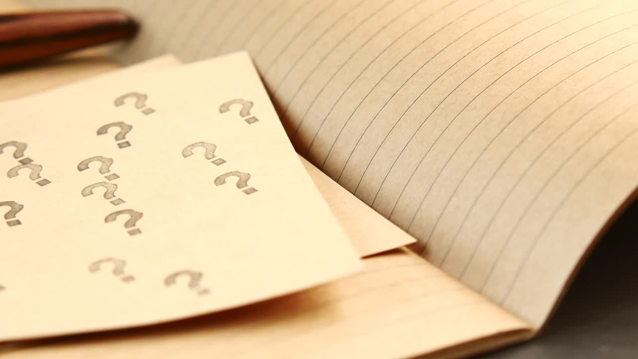 Close up of question marks on a notepad with a pen