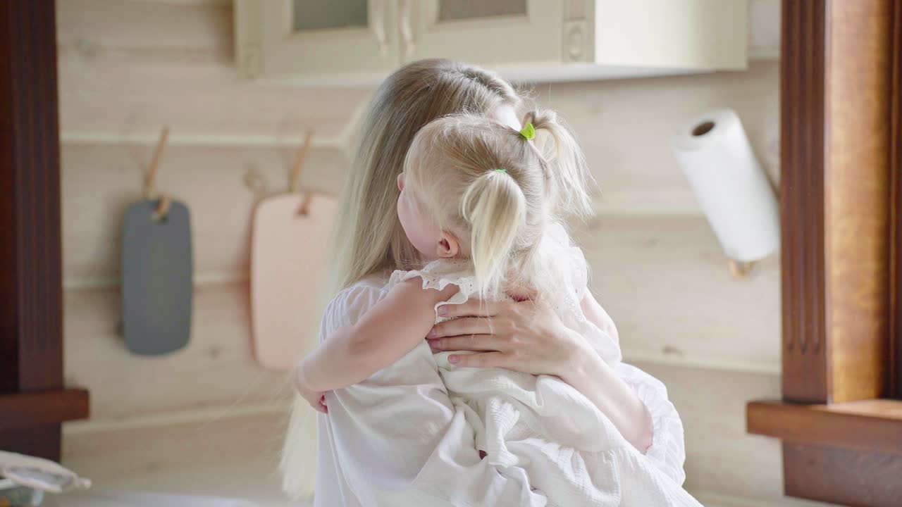 Mamma che tiene in braccio sua figlia in cucina