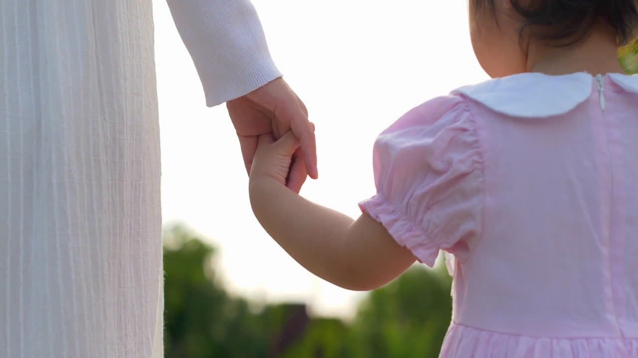 Mother And Daughter Hold Hands And Walk Through Park. Mom Kid Daughter Happy Family, Sweet Moments Of Video