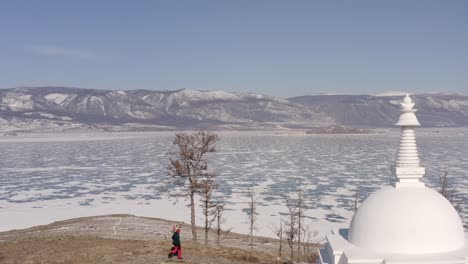 a girl walks around the buddhist stupa of enlightenment. drone take off on ogoy island