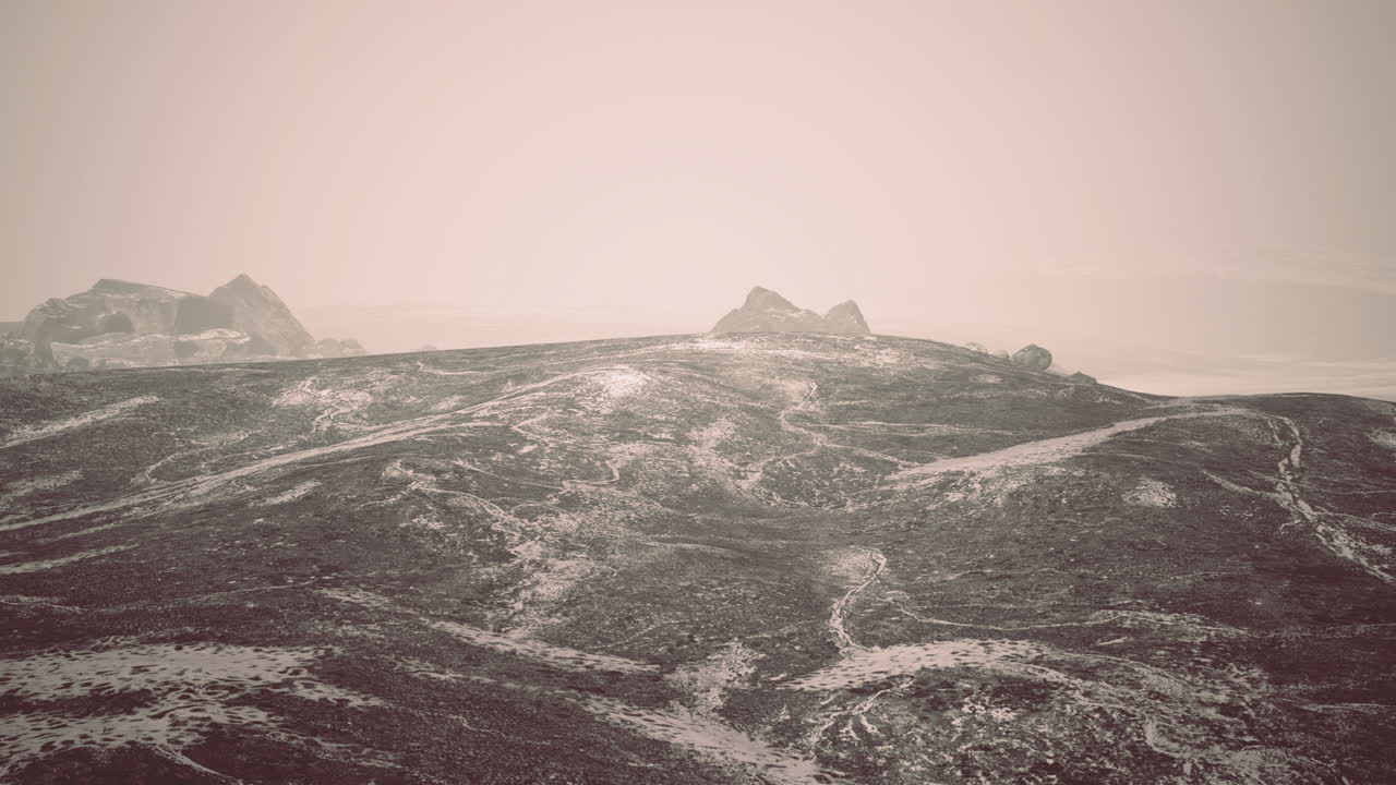 Snowy landscape with rocky formations under hazy sky at dawn