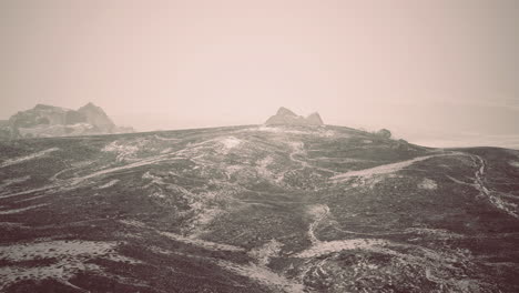 snowy landscape with rocky formations under hazy sky at dawn