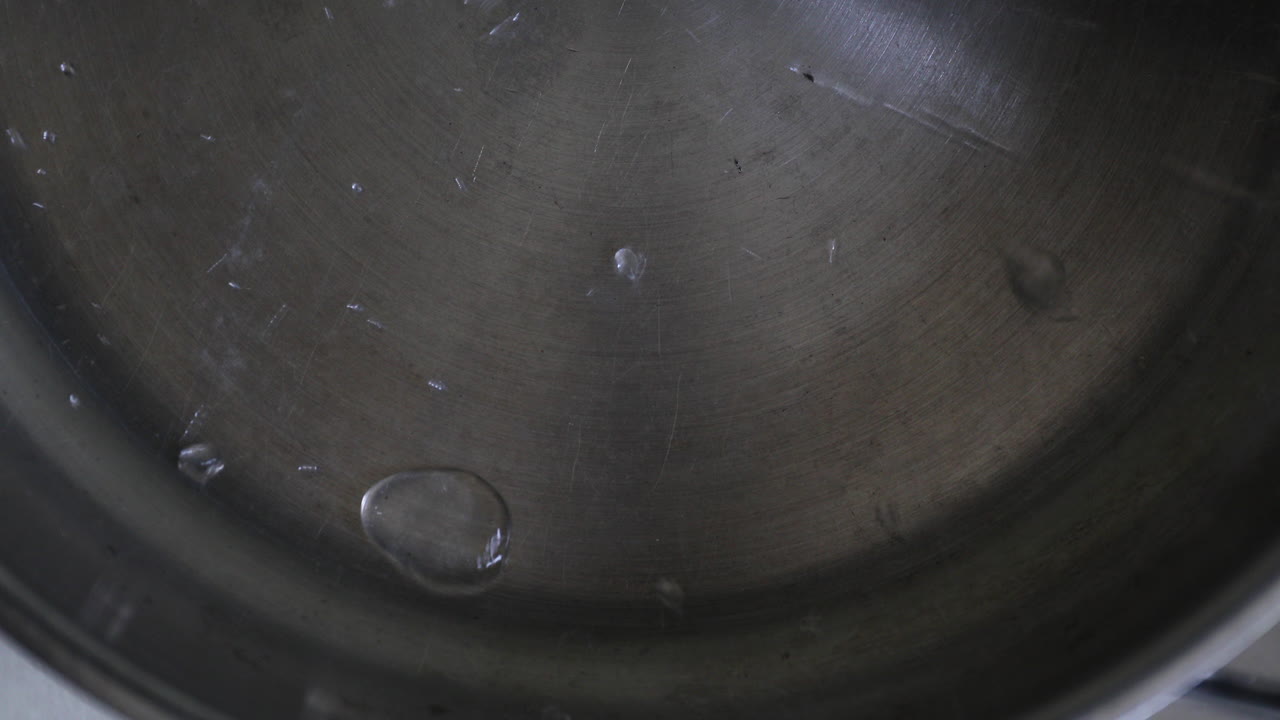 Rhythmic shaking of water drops within the pan creates a simple visual pattern