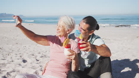 una pareja caucásica senior tomando una selfie en la playa.