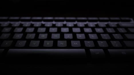 panning shot of a keyboard lit by a computer screen.