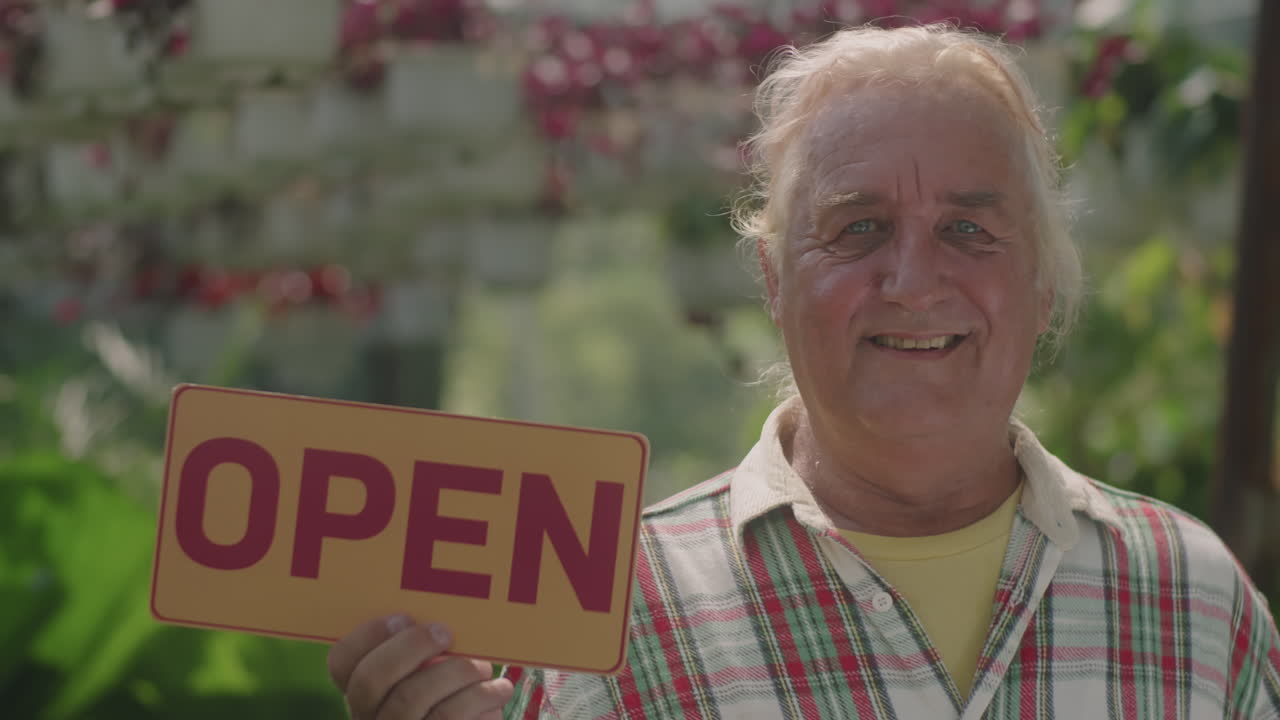 Portrait of Happy Senior Nurseryman with Open Sign