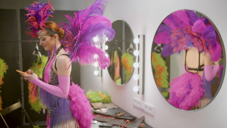 cabaret girl texting and dancing in front of a mirror