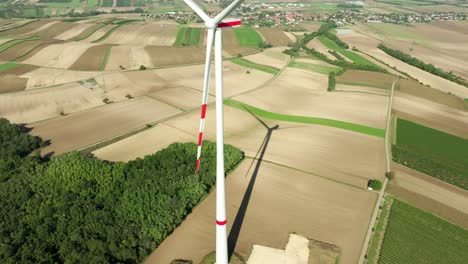 Wind-Turbine-With-Green-And-Yellow-Fields-In-Summer---aerial-drone-shot