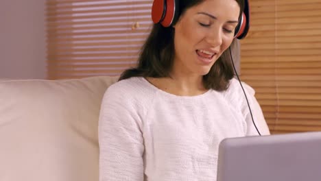 Smiling-woman-using-laptop-on-sofa-