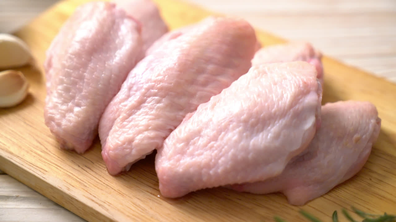 ali di pollo medie fresche crude su tavola di legno con ingredienti