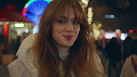 girl enjoying christmas fair under night festive lights closeup. smiling woman