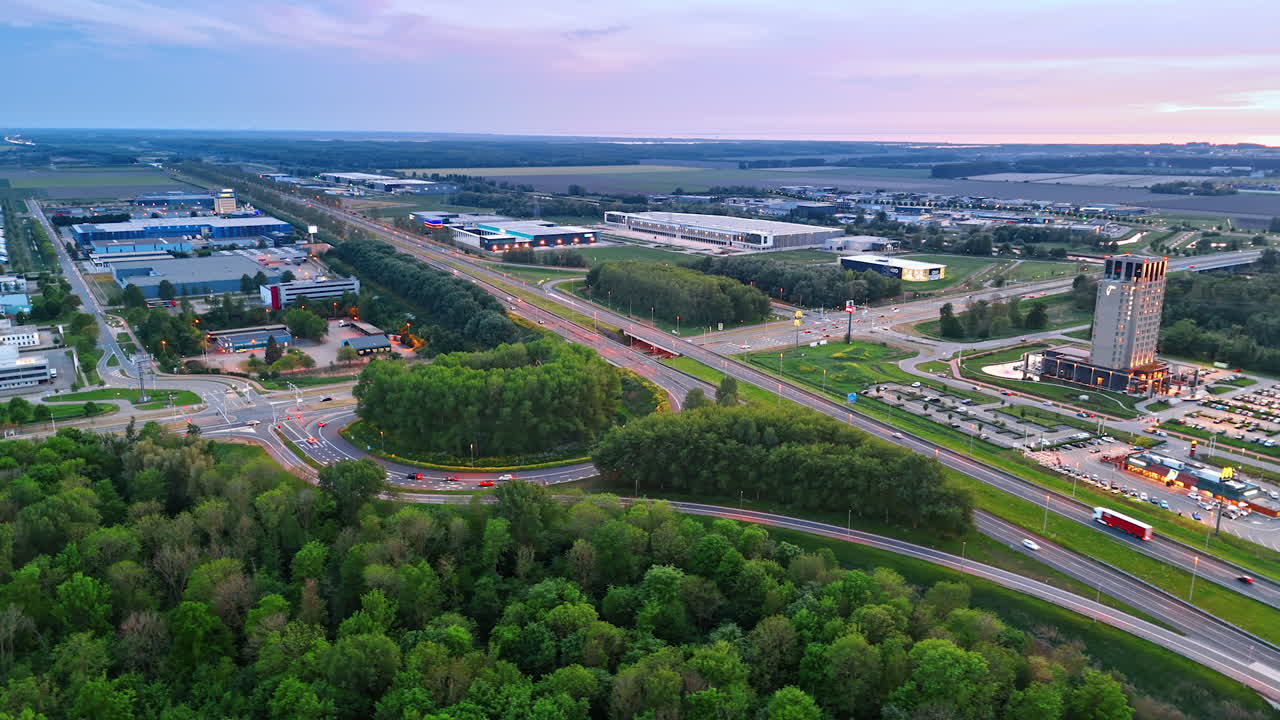 Netherlands highway at twilight. An aerial view of a highway in the Netherlands, surrounded by lush greenery and urban development during twilight