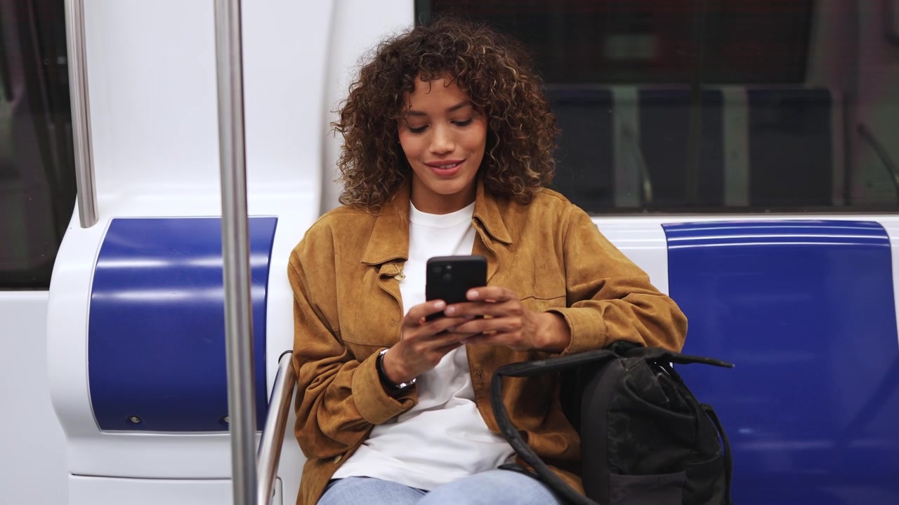 Jovem Mulher Feliz Viajando de Metrô com Smartphone