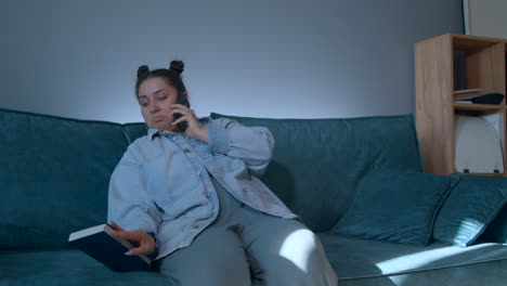 woman talking on phone and looking at a notebook on a couch