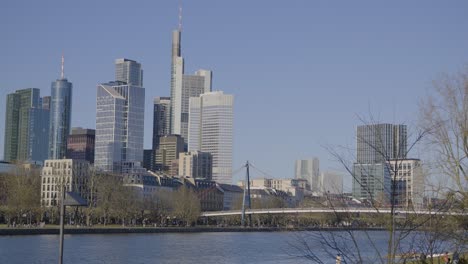 modern skyline of frankfurt, germany with river and trees in the foreground