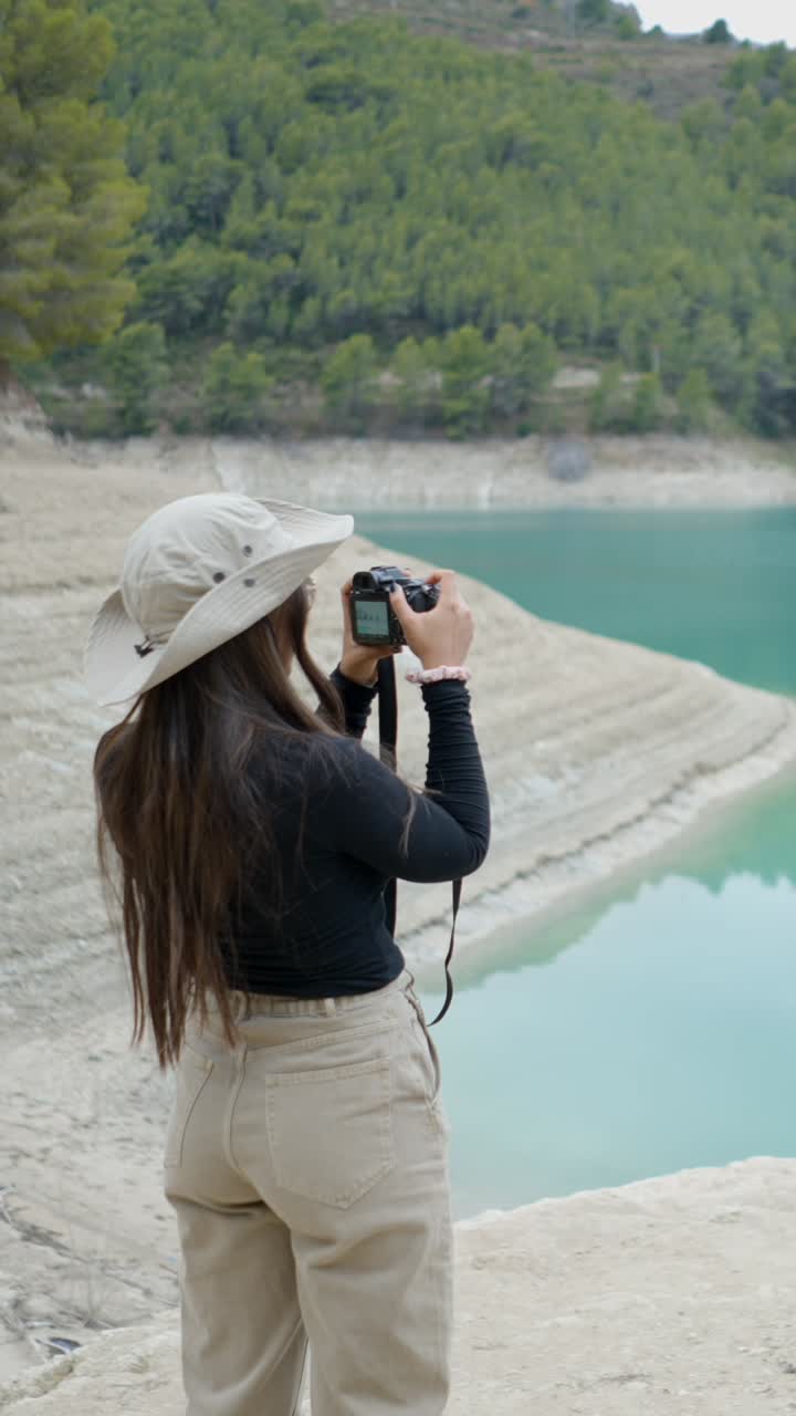 Woman Photographing a Turquoise Lake with Low Water Level