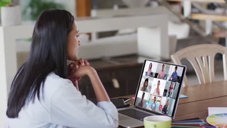 mujer caucásica usando una computadora portátil en una videollamada con colegas que trabajan desde casa