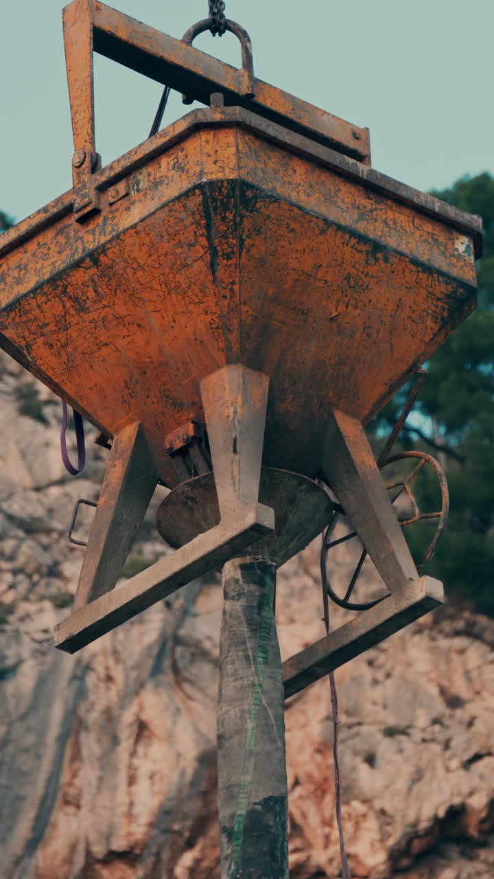 Close up of a concrete tub mounted on a tower crane for construction. Vertical