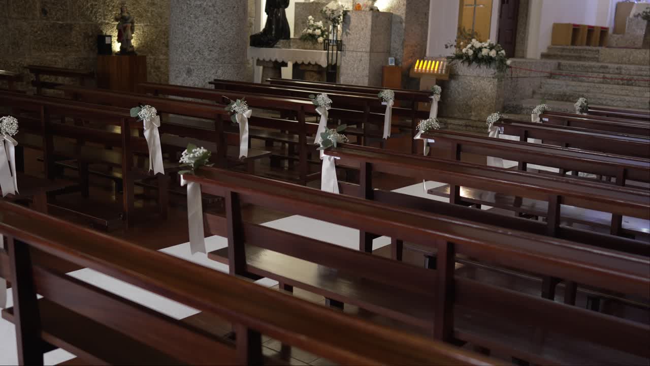 Wooden church pews decorated with delicate white flowers and ribbons for a wedding ceremony