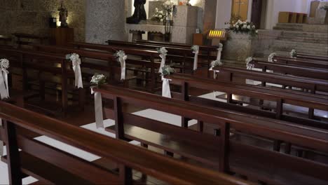 wooden church pews decorated with delicate white flowers and ribbons for a wedding ceremony