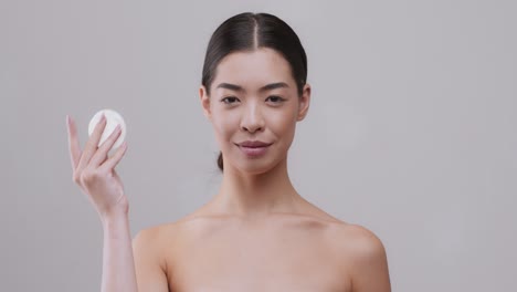 woman applying makeup remover with cotton pad