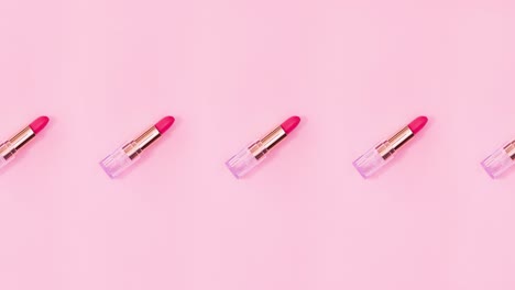 los lápices de labios rosados giran sobre un fondo rosado brillante. detenga el movimiento