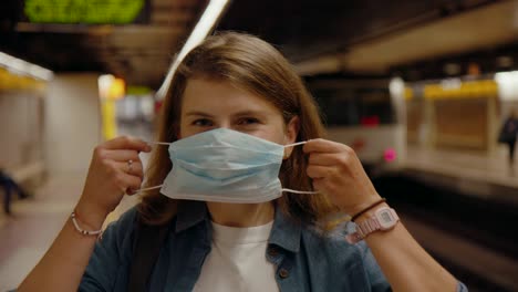 young woman at metro stop in coronavirus face mask