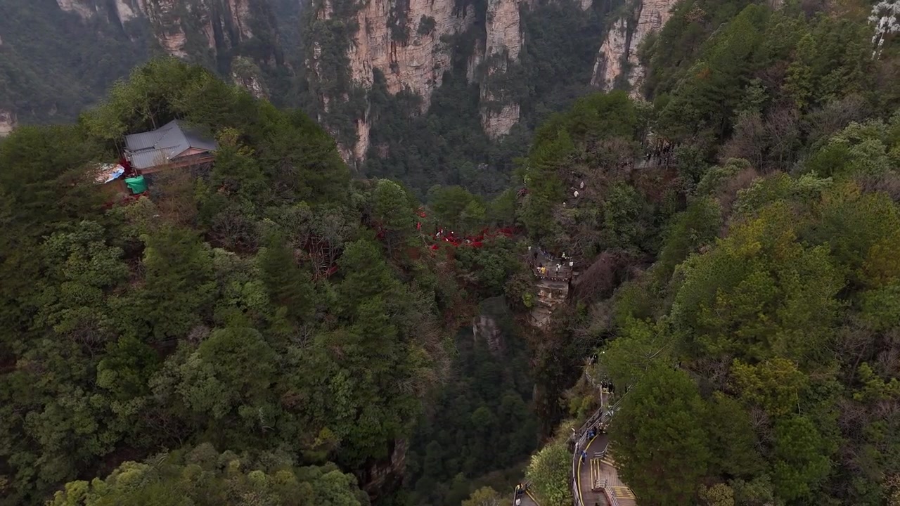 Aerial View of the first bridge under heaven in Zhangjiajie National Forest Park china showing a natural rock arch with tourists walking to a sandstone pillar.