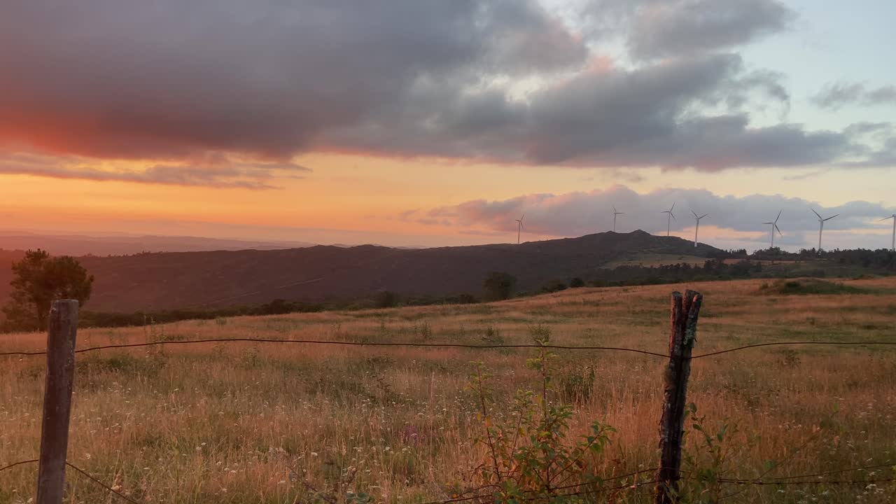 Set of wind turbines spinning in middle of rural countryside at incredible sunset in Spain