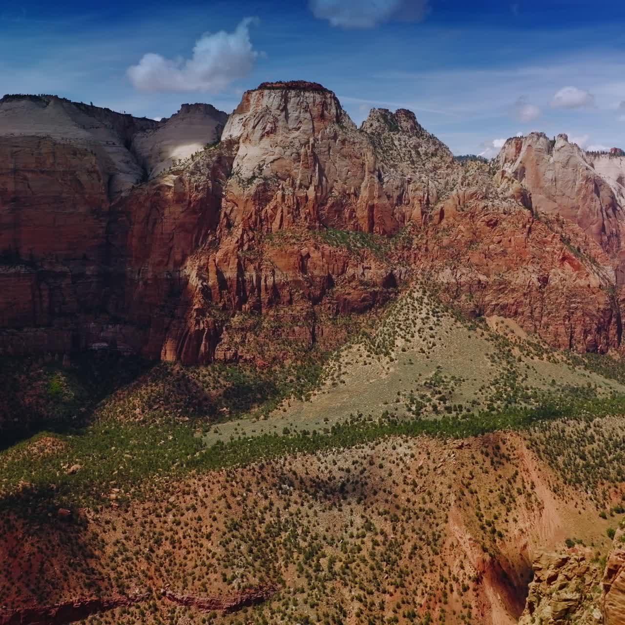 Drone flying into the crack between beautiful canyons. Clouds over the mountains throwing shadows on rocks