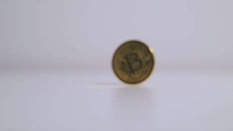 gold bitcoin coin is spun in slow motion on a white surface, digital finance