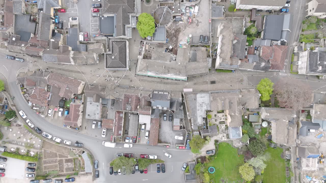 Vertical aerial of Corsham high street grid with stone rooftops, narrow gardens and vehicles lining central roadway, punctuated by mature trees