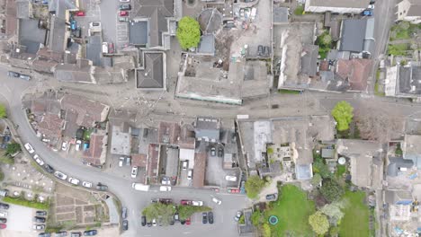 vertical aerial of corsham high street grid with stone rooftops, narrow gardens and vehicles lining central roadway, punctuated by mature trees