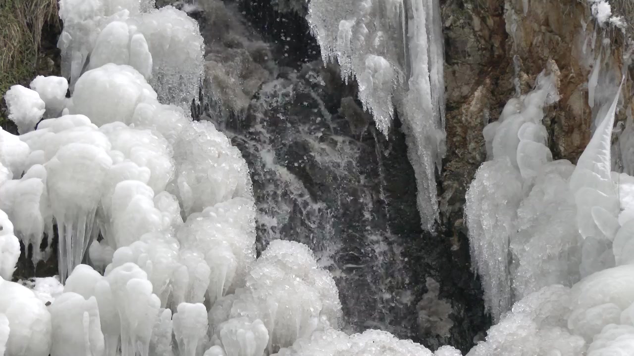 Piccola cascata che scorre attraverso formazioni di ghiaccio in inverno