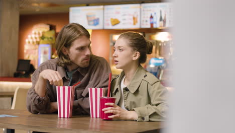 Loving-Couple-Eating-Popcorn-And-Talking-Together-At-The-Cinema-Snack-Bar-1