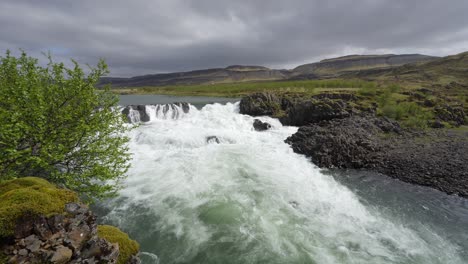 the stunning nordic landscape with a roaring waterfall and mountains in the distance