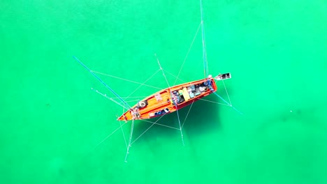 Beautiful-fishing-boat-with-rods-bent-over-calm-water-of-turquoise-shallow-lagoon-on-a-sunny-summer-day-in-Philippines