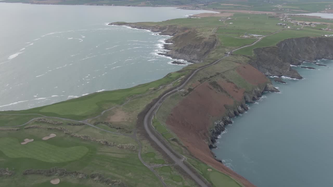 Aerial flight over irish golf course towards costal shoreline and flying over empty road