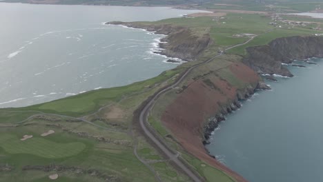 aerial flight over irish golf course towards costal shoreline and flying over empty road