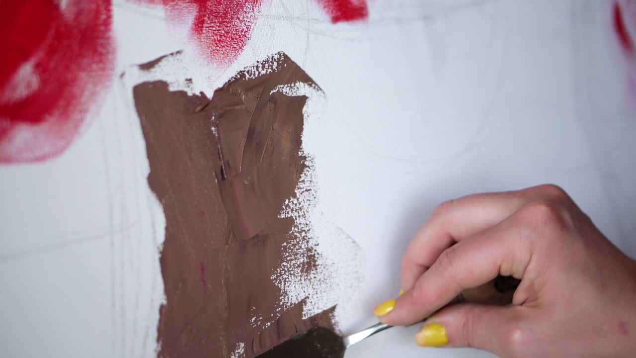 인식할 수 없는 예술가가 캔버스에 새로운 예술 작품을 만들어 그림을 그립니다. 예술가는 스파 ⁇ 라, 푸티 칼을 사용하여  ⁇  캔버스에 갈색 페인트를 적용합니다. 클로즈업