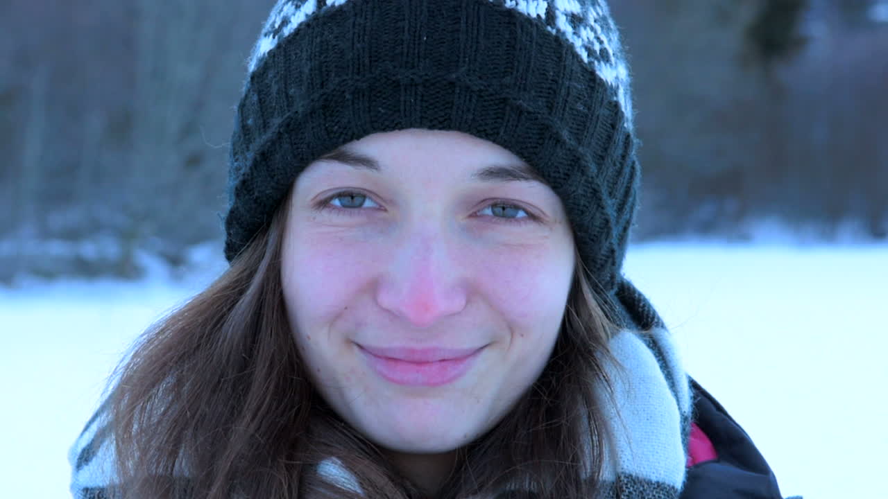 ragazza francese con cappello in inverno sorridente al rallentatore nella fotocamera con la neve intorno