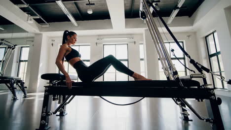woman doing pilates exercise on a reformer machine in a modern studio