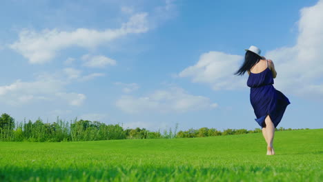 a stylish pregnant woman in a light dress carefree walks along a green meadow past the camera 2