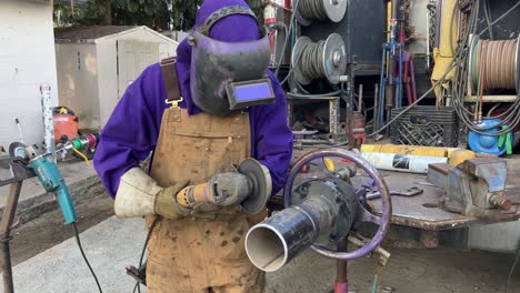 close-up shot of a man using an angle grinder on a metal pipe