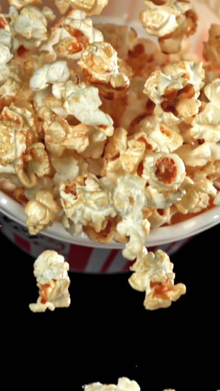 Popcorn al caramello che cadono da un contenitore a strisce