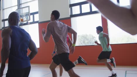 Diverse-male-basketball-team-and-coach-running-and-wearing-sportswear